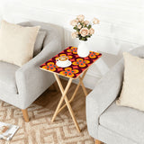 Orange Flower Power retro TV tray set of 4, next to a grey sofa with flowers