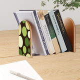 Green Dots retro bookend holding books on a wooden desk next to a pen