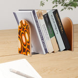 Orange Rings retro bookend holding books on a wooden desk next to a pen