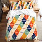 Full duvet cover set with atomic harlequin diamonds in orange, teal, navy and cream on a bed with white sheets