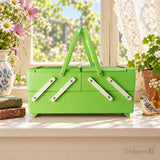 Styled illustration of a vintage 1950s lime green sewing or jewelry box with two handles on a sunny windowsill with flowers