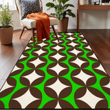 Top view of green and brown geometric area rug 3x5 ft on a wood floor beside an armchair with an orange throw