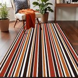 Top view of striped area rug 3x5 ft in red, orange, brown and cream on a wood floor beside an armchair with an orange throw