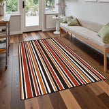 Striped area rug 3x5 ft in red, orange, brown and cream on a wood floor in front of a sofa near a glass door