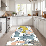 White leaf art area rug 3x5 ft in olive, pink, blue-gray laid out on the floor of a white kitchen