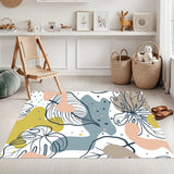 White leaf art area rug 3x5 ft in olive, pink, blue-gray in a bright room beside a wooden chair and wicker baskets
