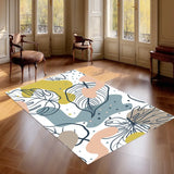 White leaf art area rug 3x5 ft in olive, pink, blue-gray on a hardwood floor in a sunlit room with tall windows and armchairs