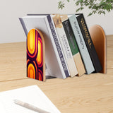 Purple Op-Art retro bookend holding books on a wooden desk next to a pen