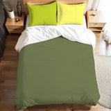 Olive green duvet cover set with lime green pillowcases on a bed with a wooden nightstand and a lamp