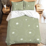 Full duvet cover set with white dandelion fluff on sage green on a bed with a wooden bedside table