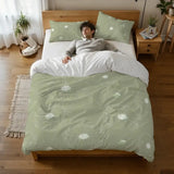 Person lying on a bed under the sage green dandelion duvet cover, seen from above