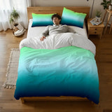 Person lying on a bed under the blue green ombre duvet cover, seen from above