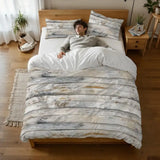 Person lying on a bed under the rustic gray wood plank duvet cover, seen from above