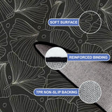 Close-up of the rug, black and gray botanical leaf line pattern, with a folded corner showing binding and backing