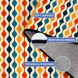 Close-up of the rug, orange, teal and navy vertical waves, with a folded corner showing binding and backing