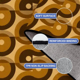 Close-up of the rug, brown and mustard interlocking swirls, with a folded corner showing binding and backing