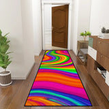 Rainbow swirl hallway runner rug in a hallway leading to a wooden door, with a console and plant