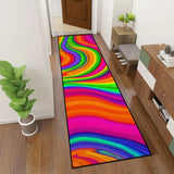 Rainbow swirl hallway runner rug in a narrow hallway next to a green plant and shoe bench