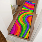Rainbow swirl hallway runner rug angled along a wooden hallway floor near stairs and a plant