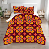 Queen comforter set with burgundy, orange and yellow flower power on a bed in a bright bedroom