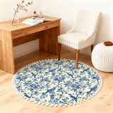 Blue toile round rug with pom poms in front of a wooden desk and white chair