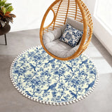 Blue toile round rug with pom poms under a hanging rattan egg chair