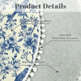 Close-up of blue toile round rug with gray backing and white pom pom trim