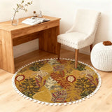 Mustard leaf-print round rug with pom poms in front of a wooden desk and white chair