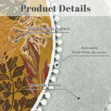 Close-up of mustard leaf-print round rug with gray backing and white pom pom trim