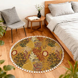 Mustard leaf-print round rug with pom poms beside a bed and small wooden side table