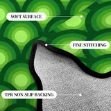 Close-up of green bubble-pattern scalloped rug corner with black binding and gray non-slip backing