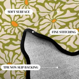 Close-up of olive green daisy-pattern scalloped rug corner with black binding and gray non-slip backing