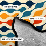 Close-up of wavy-stripe navy and orange scalloped rug corner with black binding and gray non-slip backing