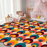 Multicolor circle-pattern scalloped area rug in a nursery with crib and pink canopy
