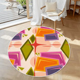 Round rug with white border and pink, orange and olive geometric shapes beside a white armchair