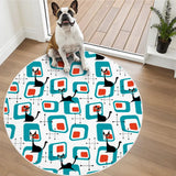Small dog sitting on a round rug with teal square pattern and black cat motifs